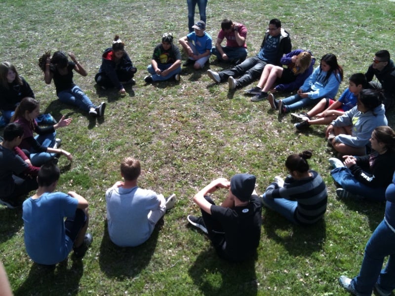 youth gathered in a circle on the grass